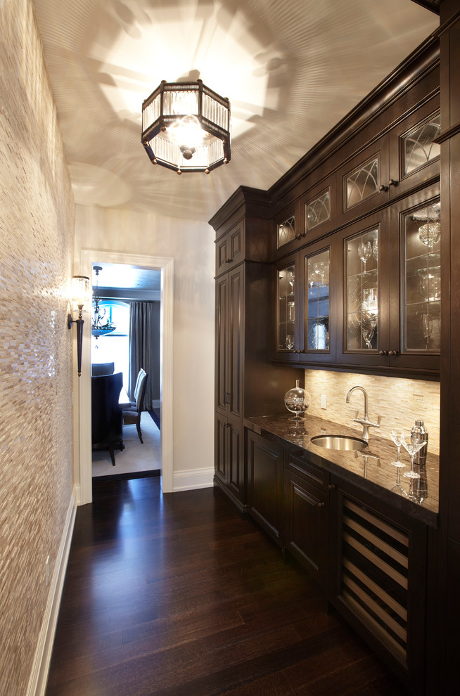 Inspiration for a large traditional single-wall wet bar in Toronto with an undermount sink, glass-front cabinets, dark wood cabinets, granite benchtops, beige splashback, matchstick tile splashback and dark hardwood floors.