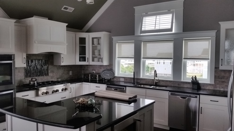 Transitional kitchen photo with a double-bowl sink, glass-front cabinets, white cabinets, quartz countertops, gray backsplash, stone tile backsplash, stainless steel appliances and an island