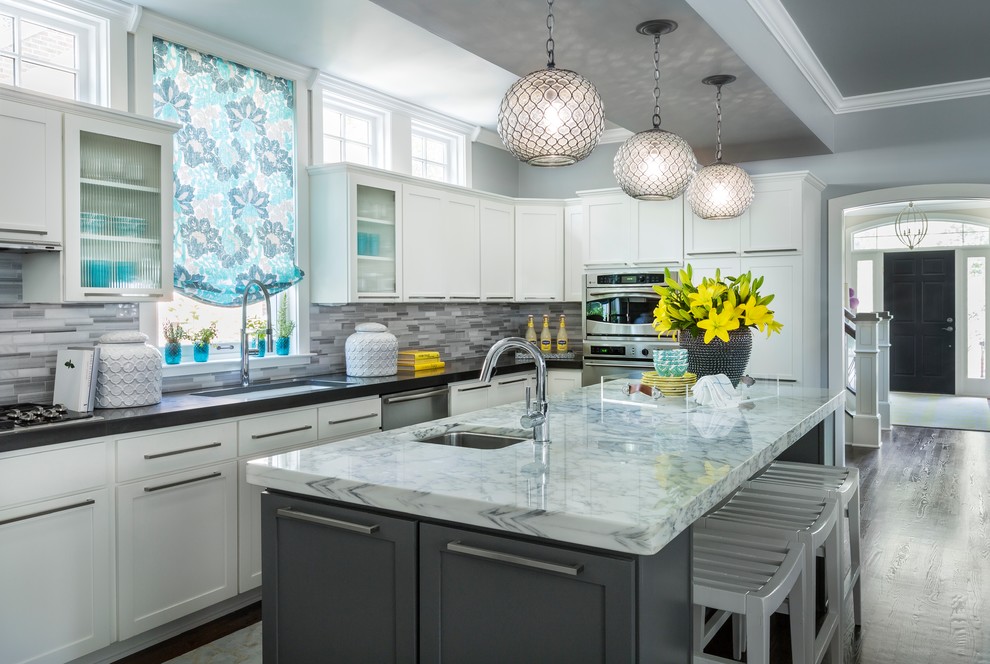 This is an example of a transitional u-shaped kitchen in Minneapolis with an undermount sink, shaker cabinets, white cabinets, grey splashback, matchstick tile splashback, dark hardwood floors, with island and stainless steel appliances.