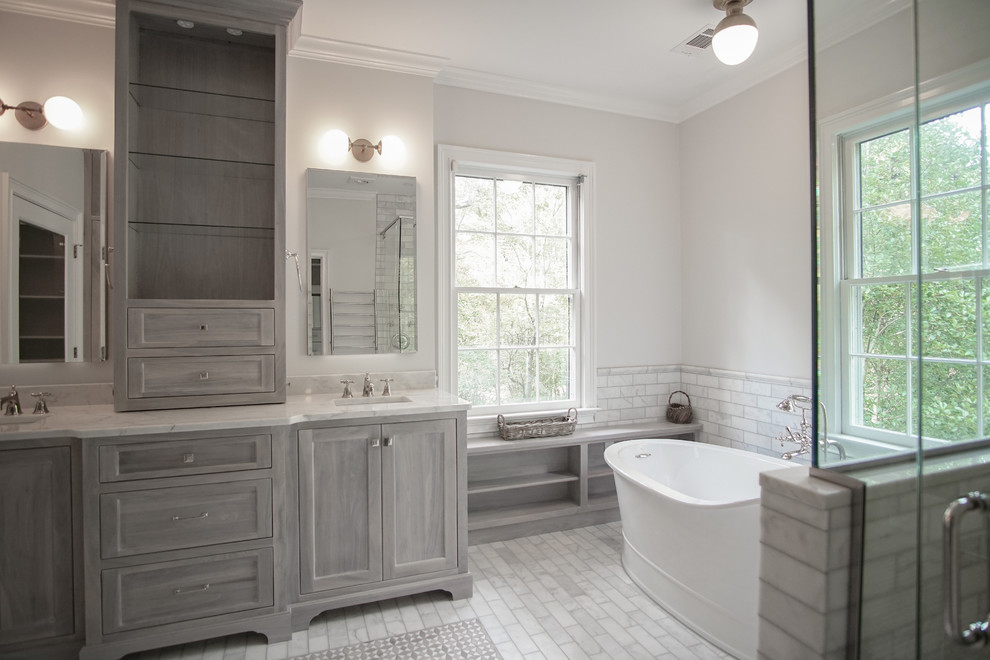Photo of a large traditional master bathroom in Atlanta with shaker cabinets, grey cabinets, a freestanding tub, a curbless shower, a one-piece toilet, gray tile, marble, white walls, marble floors, an undermount sink, marble benchtops, grey floor, a hinged shower door and white benchtops.