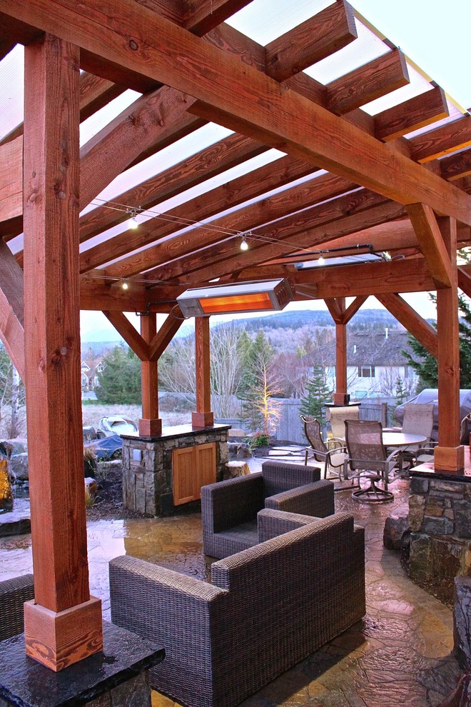 This is an example of a large traditional backyard patio in Seattle with natural stone pavers, an awning and an outdoor kitchen.