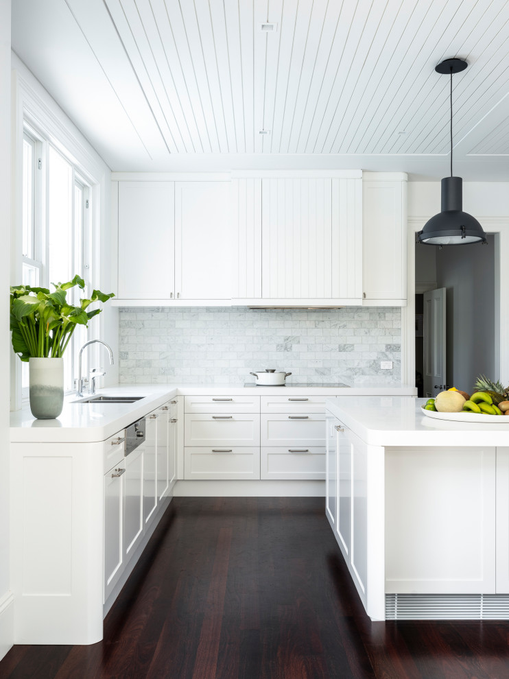 Contemporary open plan kitchen in Sydney with an undermount sink, shaker cabinets, white cabinets, solid surface benchtops, grey splashback, marble splashback, panelled appliances, dark hardwood floors, with island, brown floor, white benchtop and wood.