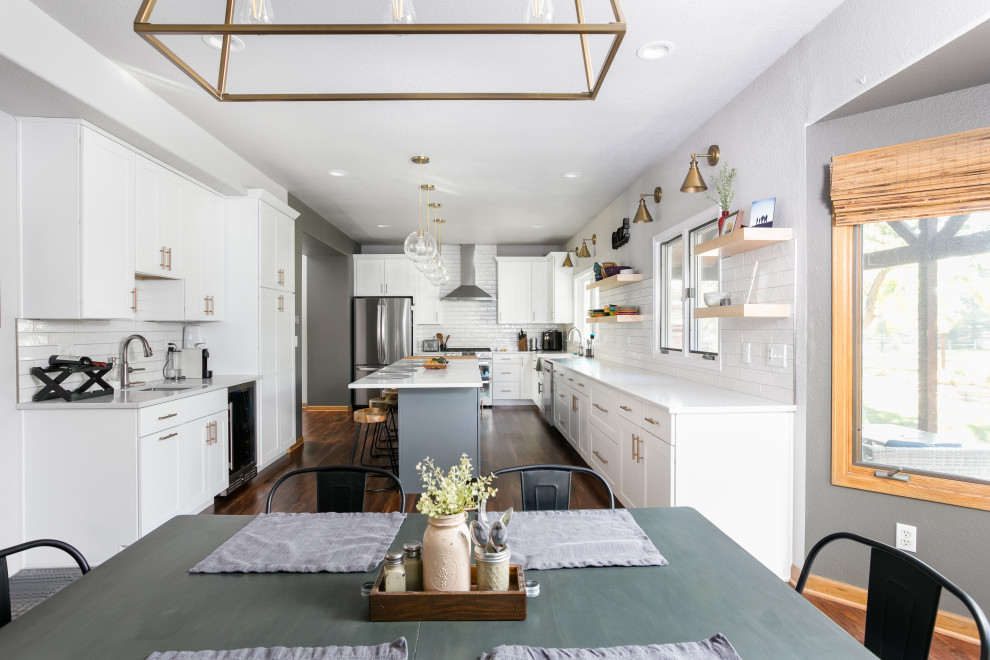 Inspiration for a large transitional u-shaped dark wood floor eat-in kitchen remodel in Denver with shaker cabinets, white cabinets, quartz countertops, white backsplash, porcelain backsplash, stainless steel appliances, an island and white countertops