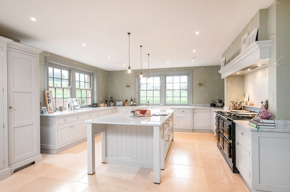 This is an example of a large country l-shaped kitchen in Hampshire with white cabinets, granite benchtops, white splashback, stone slab splashback, black appliances, porcelain floors, with island, beige floor and shaker cabinets.