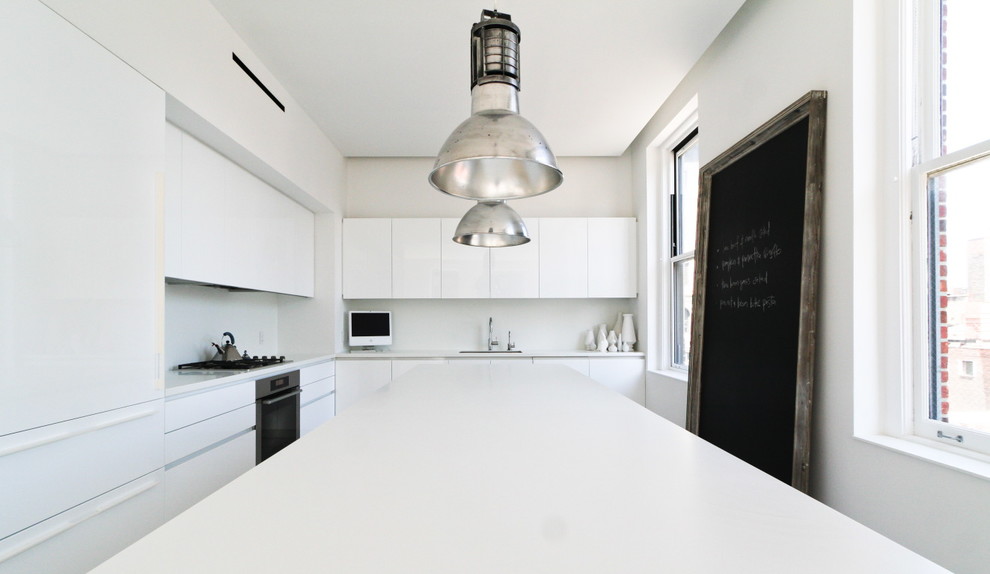 Design ideas for a scandinavian l-shaped eat-in kitchen in New York with an undermount sink, flat-panel cabinets, white cabinets, solid surface benchtops, white splashback, stainless steel appliances and light hardwood floors.