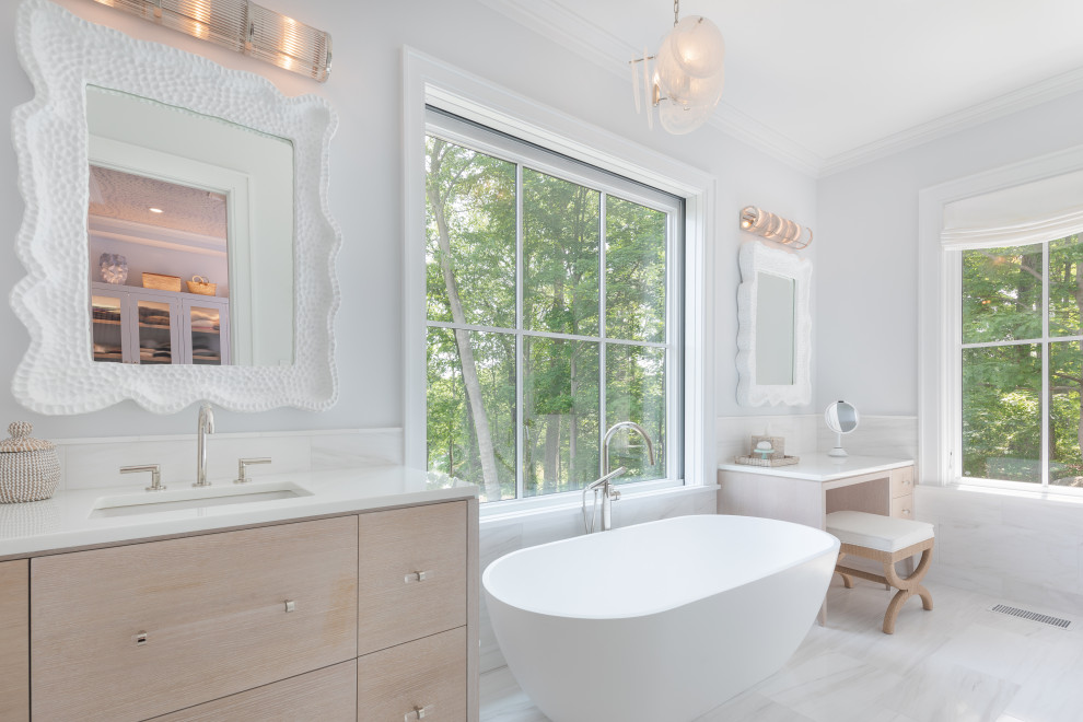 Freestanding bathtub - mid-sized transitional master white tile and stone tile marble floor, white floor and single-sink freestanding bathtub idea with flat-panel cabinets, light wood cabinets, white walls, an undermount sink, quartz countertops, white countertops and a built-in vanity