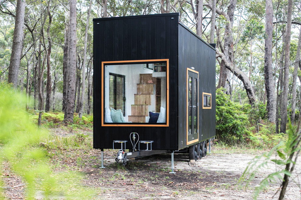 This is an example of a contemporary black exterior with wood siding, a flat roof and a metal roof.