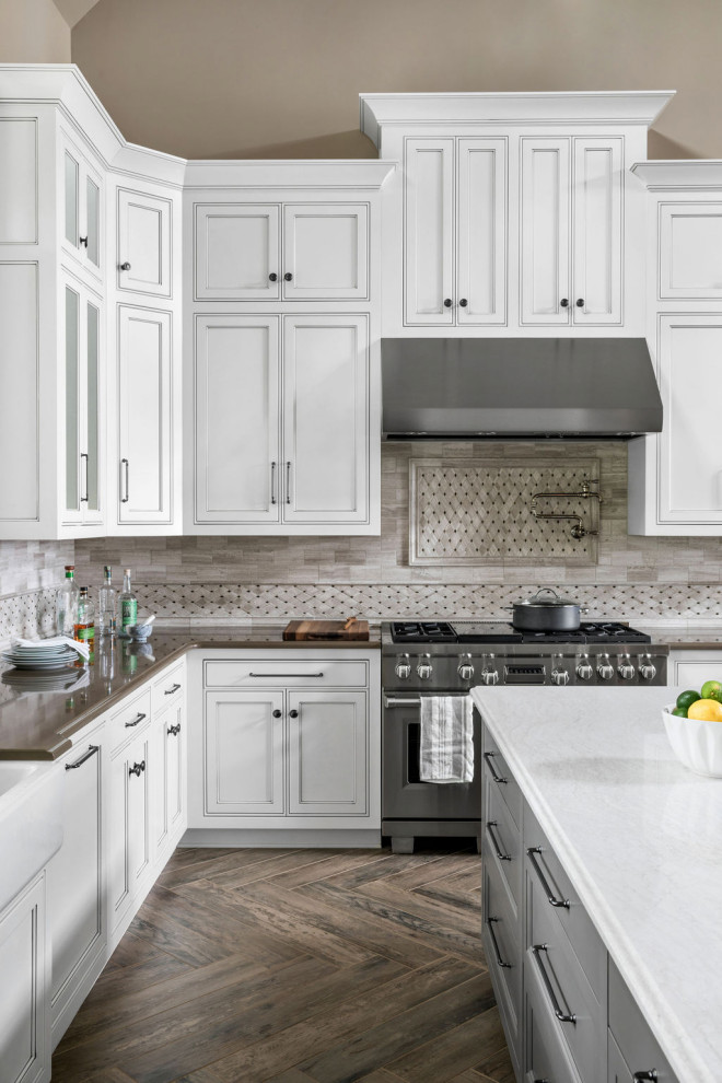 Inspiration for an expansive u-shaped open plan kitchen in Atlanta with a farmhouse sink, recessed-panel cabinets, white cabinets, quartz benchtops, grey splashback, marble splashback, stainless steel appliances, porcelain floors, multiple islands, brown floor, white benchtop and vaulted.