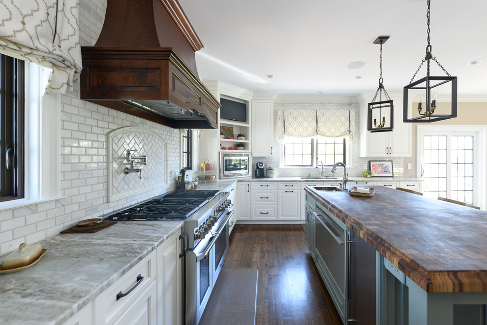 Inspiration for a large transitional l-shaped dark wood floor and brown floor kitchen remodel with an undermount sink, raised-panel cabinets, white cabinets, quartzite countertops, white backsplash, marble backsplash, stainless steel appliances and an island