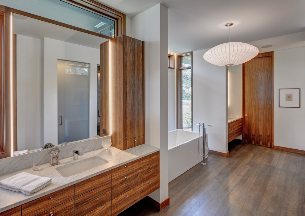 This is an example of a contemporary bathroom in Detroit with flat-panel cabinets, medium wood cabinets, a freestanding tub, white walls, dark hardwood floors, an undermount sink, brown floor, grey benchtops, a single vanity and a floating vanity.
