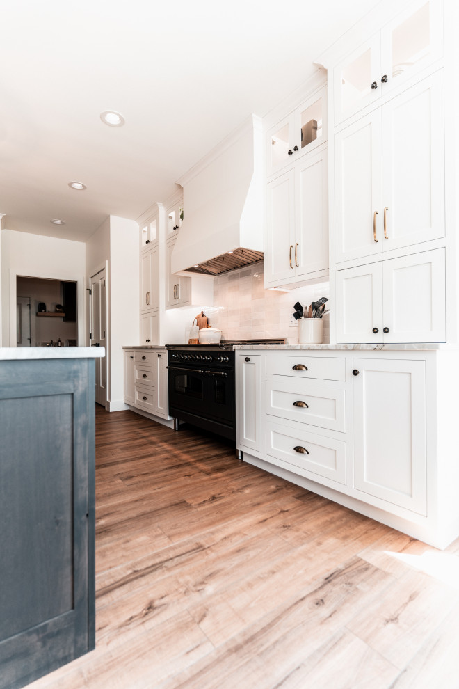 Example of a large transitional l-shaped light wood floor open concept kitchen design with an undermount sink, shaker cabinets, white cabinets, quartzite countertops, multicolored backsplash, porcelain backsplash, stainless steel appliances and an island