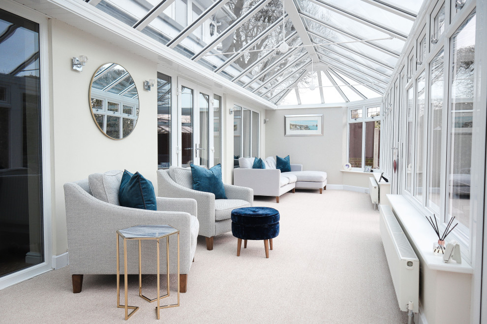 This is an example of a transitional sunroom in Essex with carpet, a glass ceiling and beige floor.