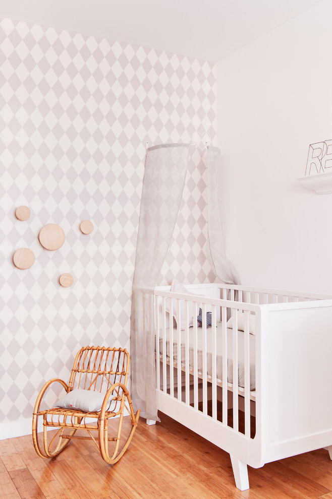 Diseño de habitación de bebé niña campestre con paredes multicolor y suelo de madera clara