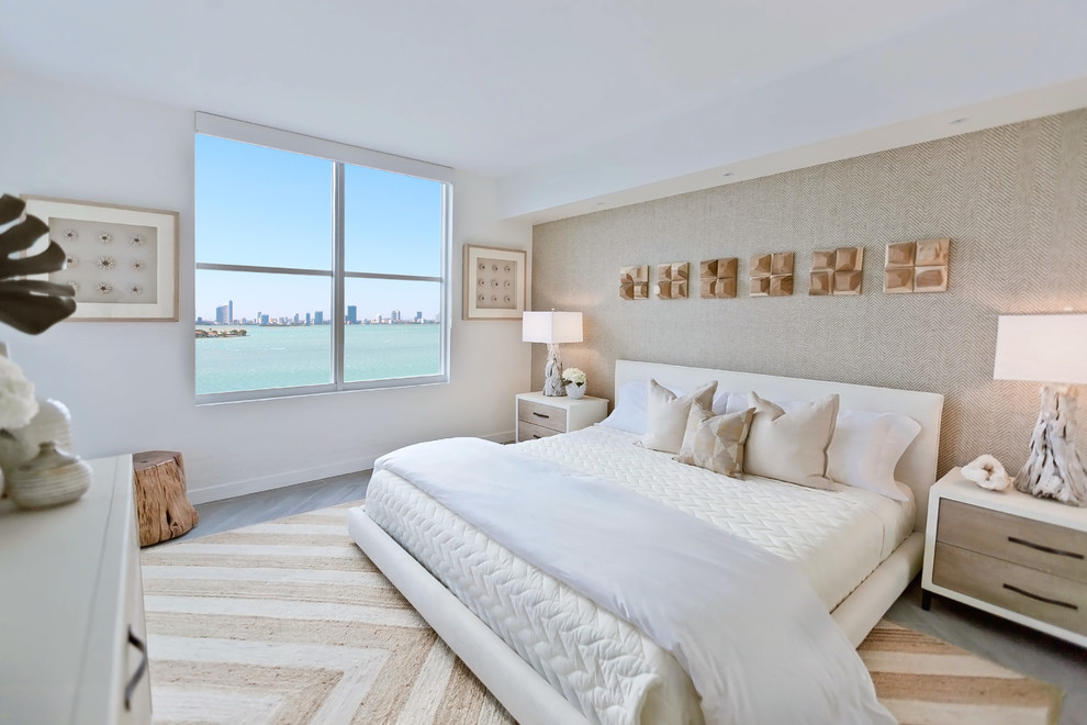 Design ideas for a beach style master bedroom in Miami with beige walls, light hardwood floors and beige floor.