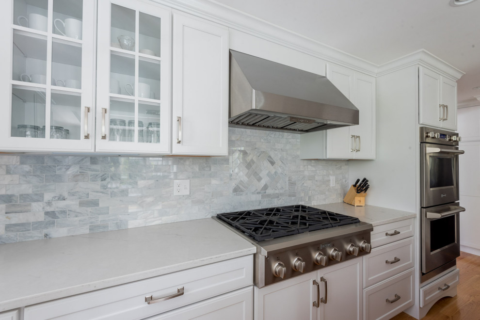 Large transitional l-shaped medium tone wood floor, brown floor and coffered ceiling eat-in kitchen photo in Boston with an undermount sink, shaker cabinets, white cabinets, quartz countertops, gray backsplash, subway tile backsplash, stainless steel appliances, an island and white countertops