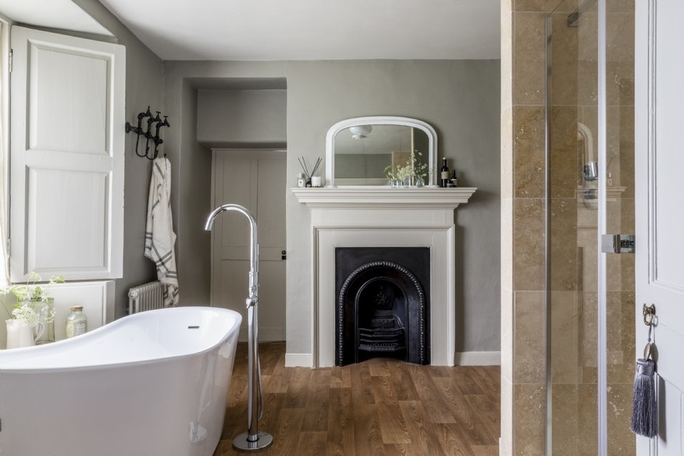 Mid-sized traditional master bathroom in Devon with a freestanding tub, a corner shower, grey walls, brown floor, a sliding shower screen, beige tile and medium hardwood floors.