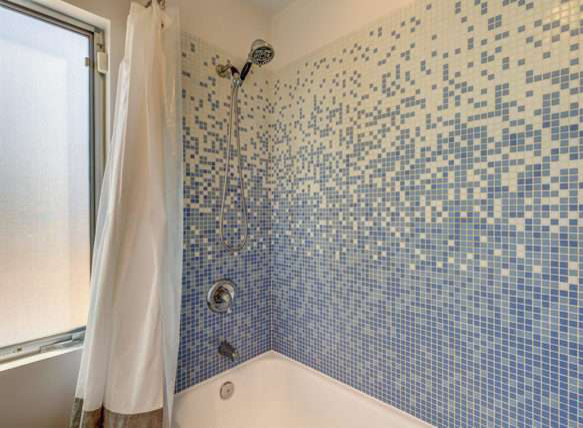 Mid-sized bathroom in Los Angeles with flat-panel cabinets, medium wood cabinets, an alcove tub, a two-piece toilet, blue tile, mosaic tile, white walls, concrete floors, a trough sink, tile benchtops, grey floor and a shower curtain.