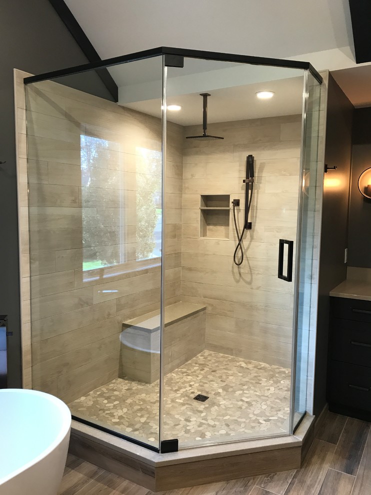 Design ideas for a mid-sized country master bathroom in Philadelphia with dark wood cabinets, a freestanding tub, a corner shower, a one-piece toilet, light hardwood floors, a hinged shower door, shaker cabinets, beige tile, porcelain tile, brown walls, an undermount sink and solid surface benchtops.