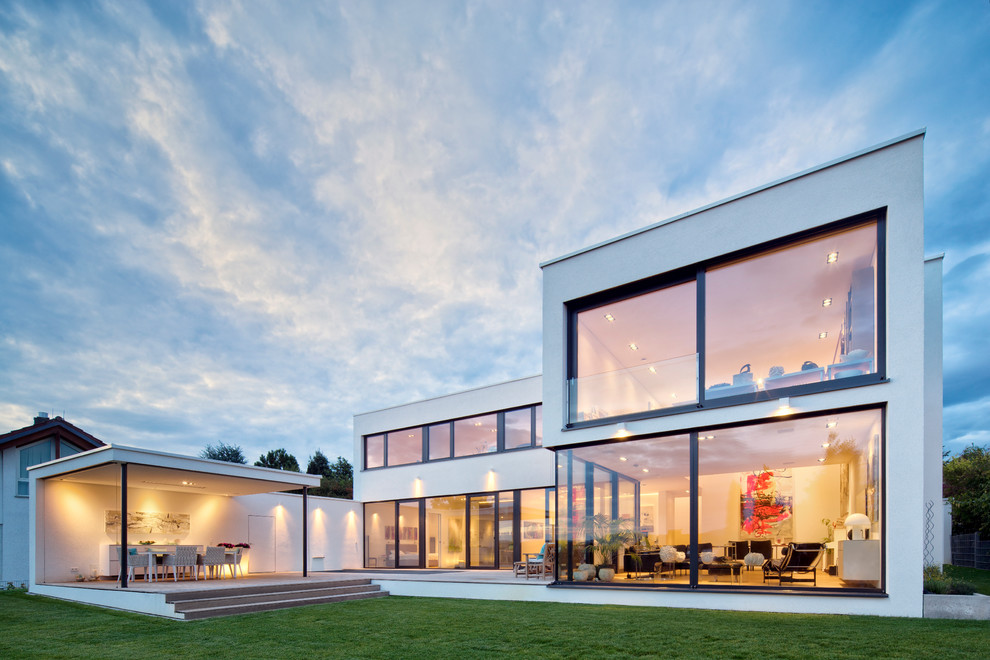 This is an example of a large modern two-storey white exterior in Stuttgart with a flat roof.