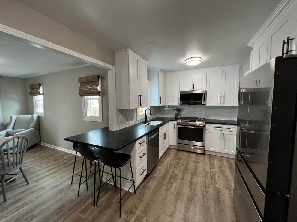 Mid-sized transitional l-shaped vinyl floor eat-in kitchen photo in Cleveland with shaker cabinets, white cabinets, granite countertops, white backsplash and black countertops