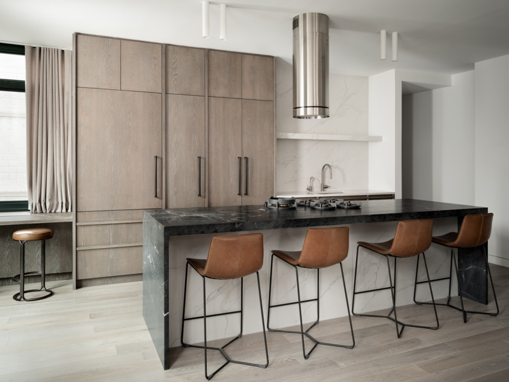 Kitchen - contemporary galley medium tone wood floor and brown floor kitchen idea in New York with an undermount sink, flat-panel cabinets, medium tone wood cabinets, white backsplash, stone slab backsplash, paneled appliances, an island and black countertops
