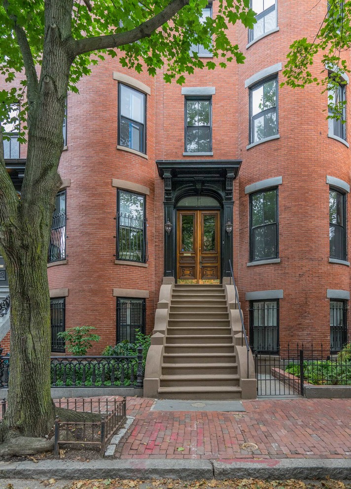 This is an example of a mid-sized traditional three-storey brick townhouse exterior in Boston with a flat roof.