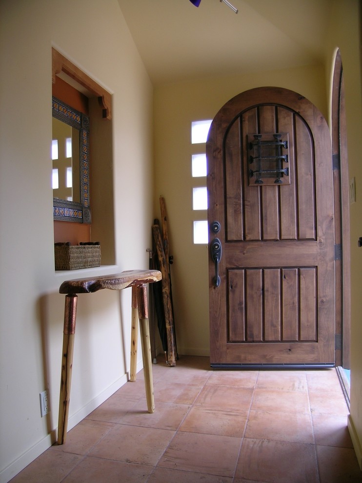 This is an example of a small front door in San Francisco with terra-cotta floors, a single front door, a dark wood front door and beige walls.