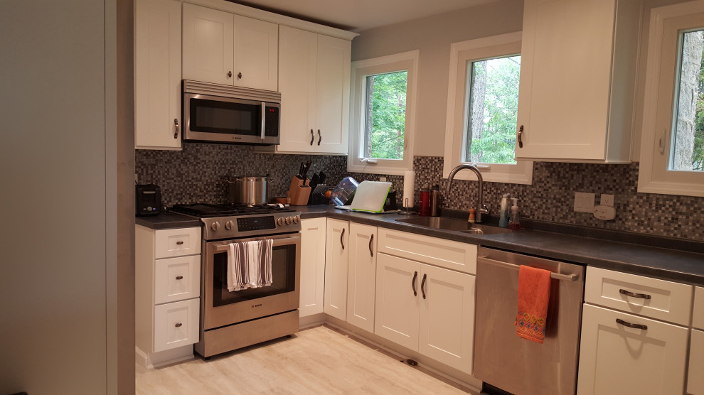 Mid-sized arts and crafts l-shaped eat-in kitchen in Other with an undermount sink, flat-panel cabinets, white cabinets, laminate benchtops, mosaic tile splashback, stainless steel appliances, vinyl floors and no island.