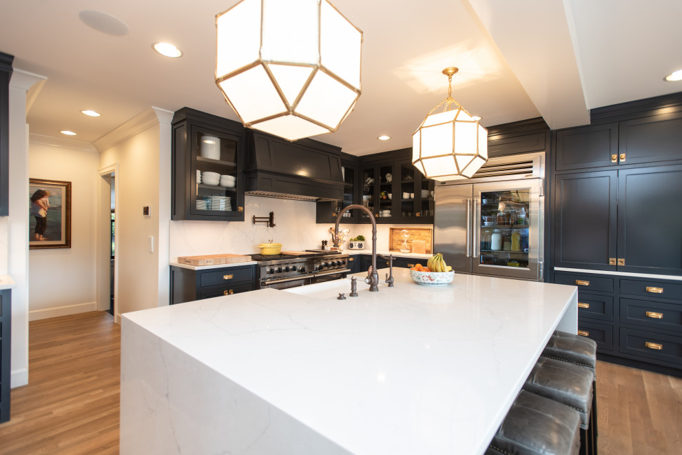 Photo of a large classic l-shaped kitchen/diner in Portland with shaker cabinets, black cabinets, medium hardwood flooring, an island, brown floors and white worktops.