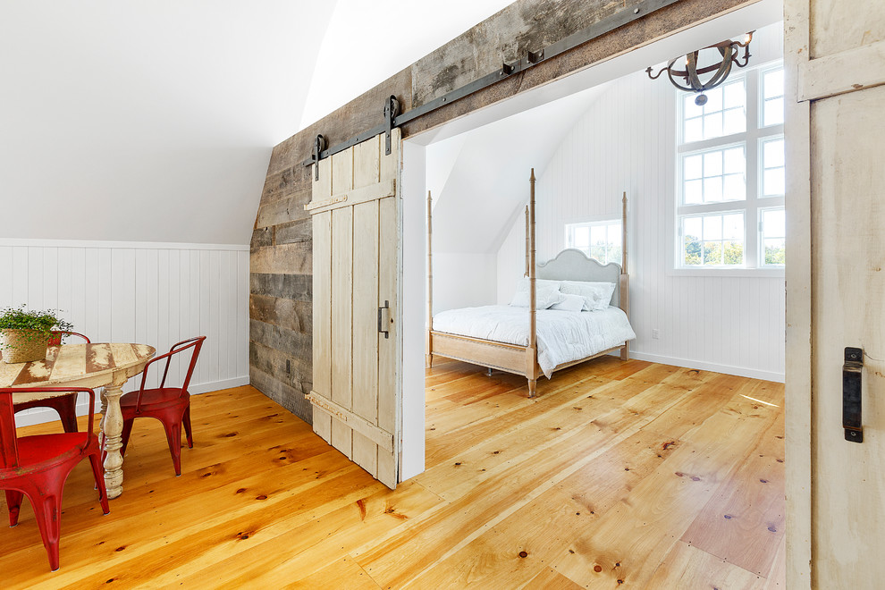Large country master bedroom in Boston with white walls, light hardwood floors, no fireplace and brown floor.