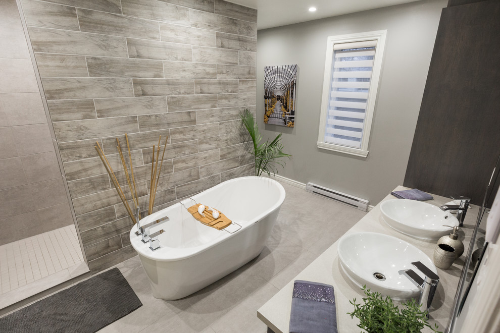 Inspiration for a large contemporary master bathroom in Montreal with a freestanding tub, an open shower, gray tile, ceramic tile, grey walls, ceramic floors, a console sink, wood benchtops, grey floor and an open shower.