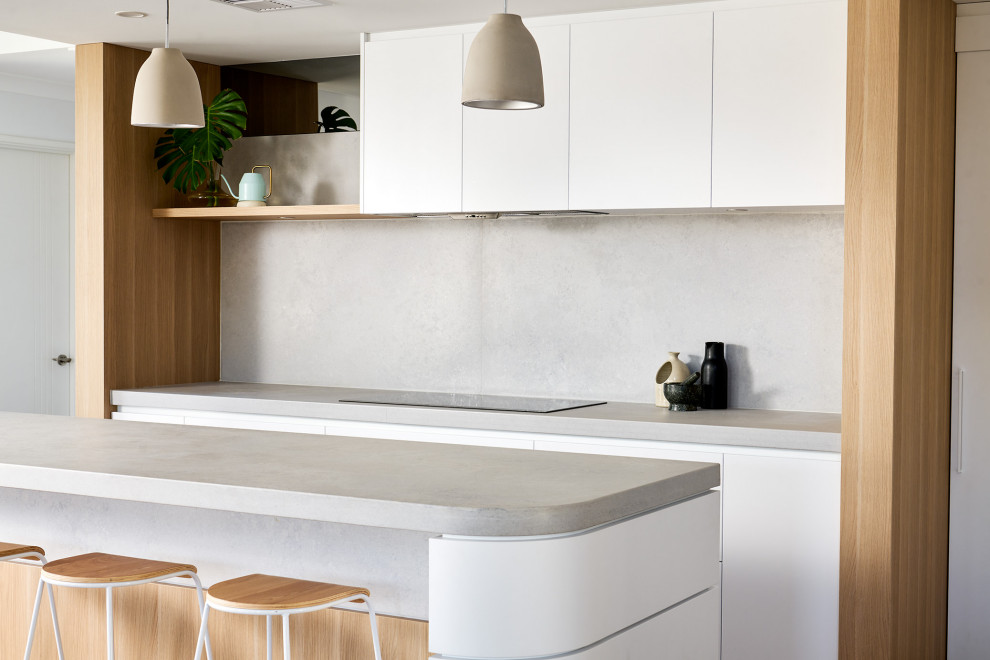 Photo of a large scandinavian l-shaped eat-in kitchen in Perth with a double-bowl sink, flat-panel cabinets, white cabinets, quartz benchtops, grey splashback, engineered quartz splashback, black appliances, medium hardwood floors, with island, brown floor and grey benchtop.
