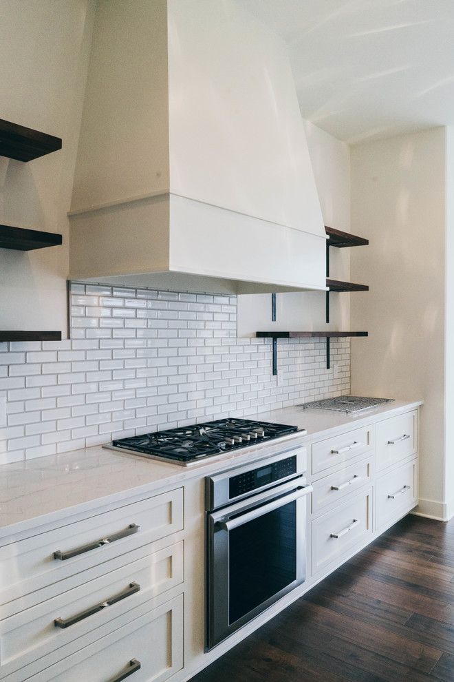 Enclosed kitchen - transitional dark wood floor enclosed kitchen idea in Omaha with a farmhouse sink, shaker cabinets, white cabinets, quartz countertops, white backsplash, paneled appliances and an island