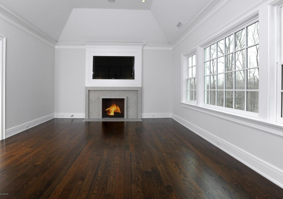 This is an example of a mid-sized traditional master bedroom in Other with grey walls, medium hardwood floors, a standard fireplace, a tile fireplace surround and brown floor.