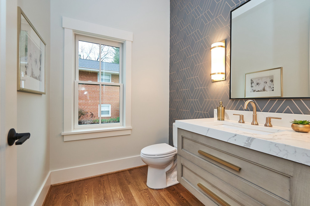 Design ideas for a mid-sized transitional powder room in DC Metro with shaker cabinets, white cabinets, a two-piece toilet, multi-coloured walls, medium hardwood floors, an undermount sink, engineered quartz benchtops, brown floor, white benchtops, a floating vanity and wallpaper.