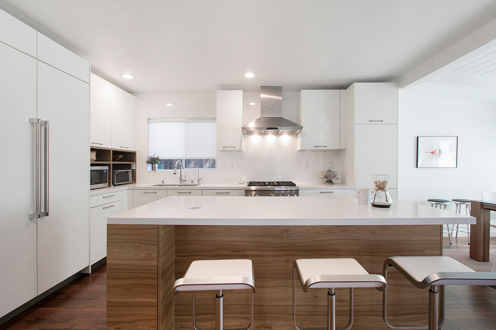 Design ideas for a mid-sized contemporary l-shaped eat-in kitchen in Los Angeles with a drop-in sink, flat-panel cabinets, medium wood cabinets, quartzite benchtops, white splashback, porcelain splashback, stainless steel appliances, laminate floors, with island, brown floor and white benchtop.