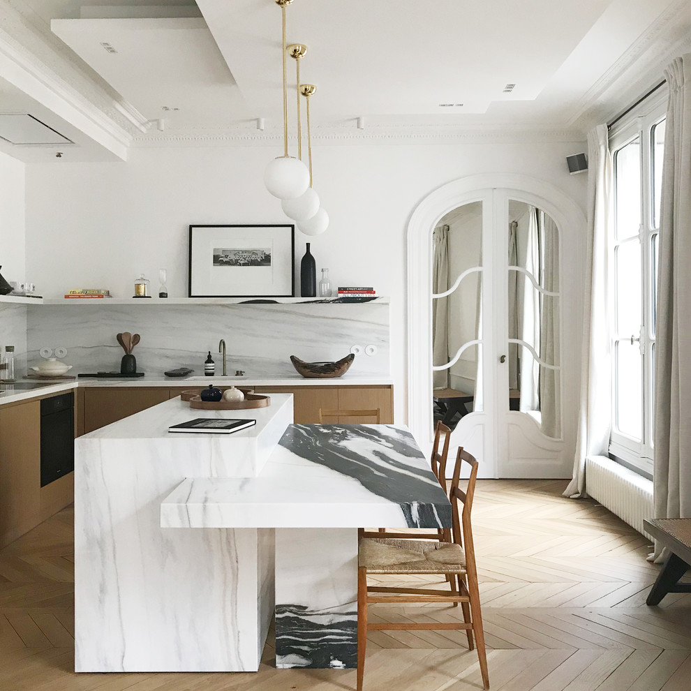 Contemporary l-shaped kitchen in Paris with light wood cabinets, white splashback, stone slab splashback, light hardwood floors, with island, beige floor and white benchtop.