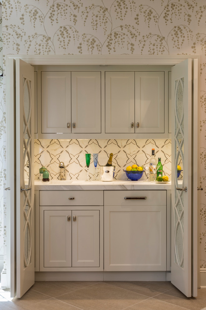 This is an example of a small transitional single-wall wet bar in New York with shaker cabinets, white cabinets, marble benchtops, multi-coloured splashback, porcelain splashback and ceramic floors.