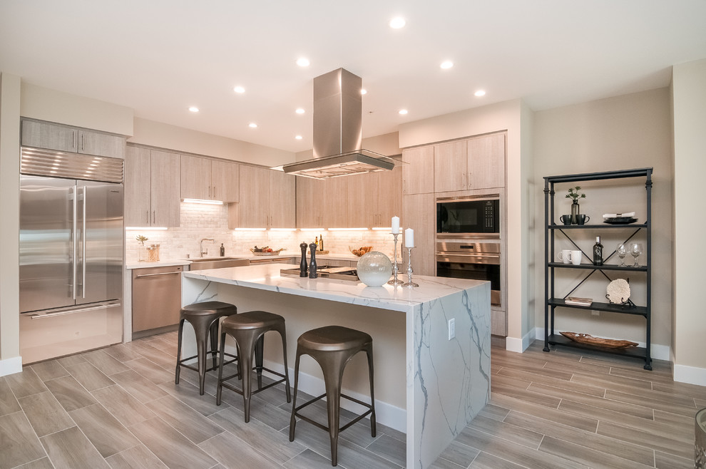 Inspiration for a contemporary l-shaped kitchen in San Diego with a farmhouse sink, flat-panel cabinets, light wood cabinets, white splashback, stainless steel appliances, with island and grey floor.