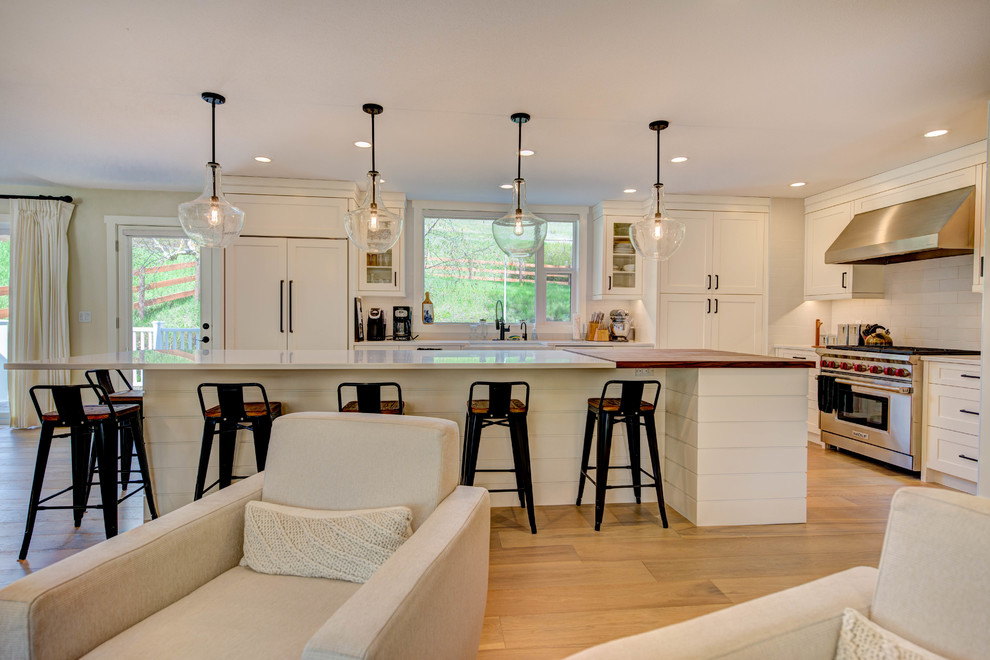Eat-in kitchen - mid-sized transitional l-shaped medium tone wood floor and beige floor eat-in kitchen idea in Vancouver with an undermount sink, shaker cabinets, white cabinets, quartz countertops, white backsplash, ceramic backsplash, stainless steel appliances and an island