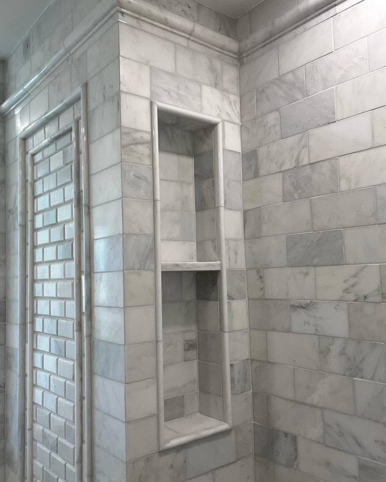 This is an example of an ensuite bathroom in New York with glass-front cabinets, white cabinets, a double shower, white tiles, marble tiles, white walls, marble flooring, marble worktops, white floors, an open shower, white worktops, a wall niche, double sinks and a floating vanity unit.