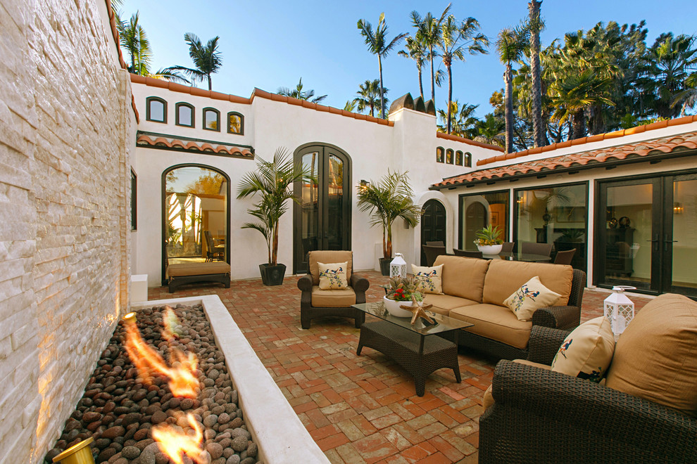 Photo of a mediterranean courtyard patio in San Diego with a fire feature, brick pavers and no cover.
