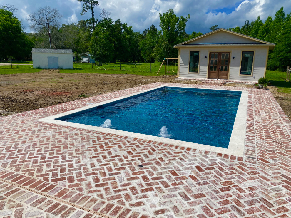 This is an example of a medium sized classic back rectangular natural swimming pool in Houston with brick paving.