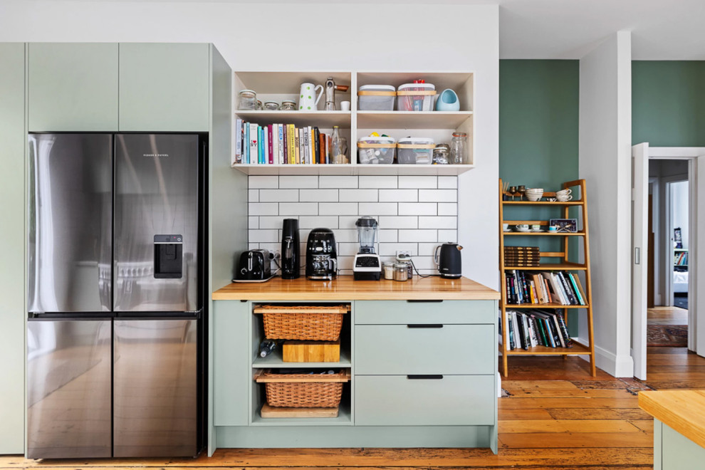 Inspiration for a medium sized contemporary galley open plan kitchen in Auckland with an integrated sink, flat-panel cabinets, green cabinets, white splashback, cement tile splashback, stainless steel appliances and a breakfast bar.