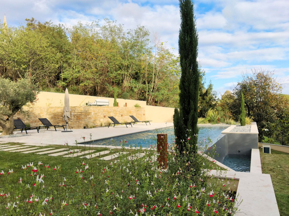Photo of a large transitional front yard rectangular infinity pool in Marseille with natural stone pavers.