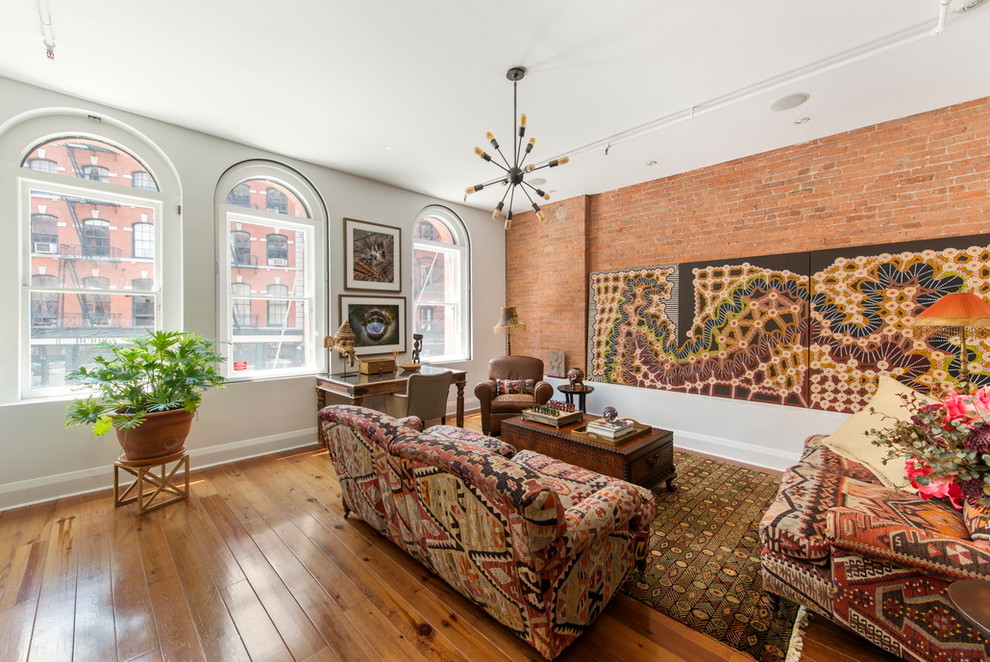 Eclectic open concept living room in New York with white walls and medium hardwood floors.