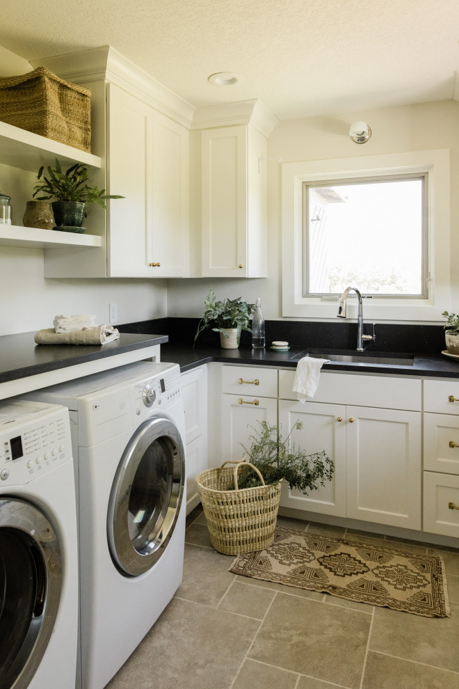 Inspiration for a mid-sized traditional u-shaped dedicated laundry room in Other with an undermount sink, recessed-panel cabinets, white cabinets, quartz benchtops, black splashback, engineered quartz splashback, white walls, ceramic floors, a side-by-side washer and dryer, grey floor and black benchtop.