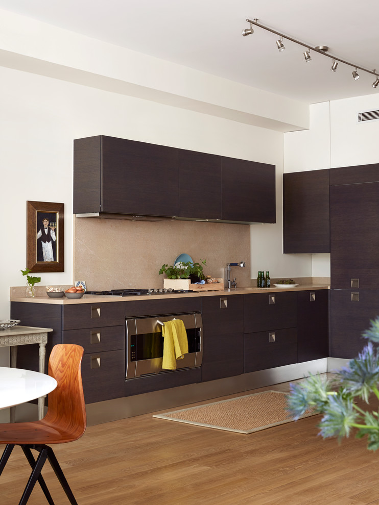 Photo of a mid-sized contemporary l-shaped open plan kitchen in Paris with an integrated sink, flat-panel cabinets, dark wood cabinets, marble benchtops, beige splashback, light hardwood floors, no island, timber splashback and stainless steel appliances.