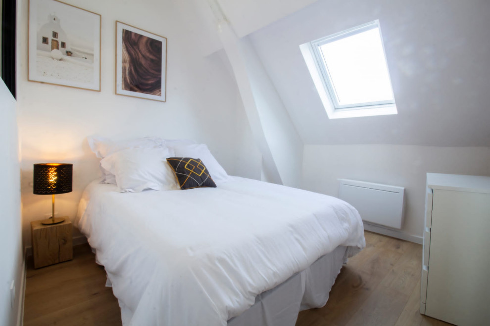 Imagen de dormitorio principal y blanco y madera actual de tamaño medio sin chimenea con paredes blancas, suelo de madera clara, suelo beige y vigas vistas