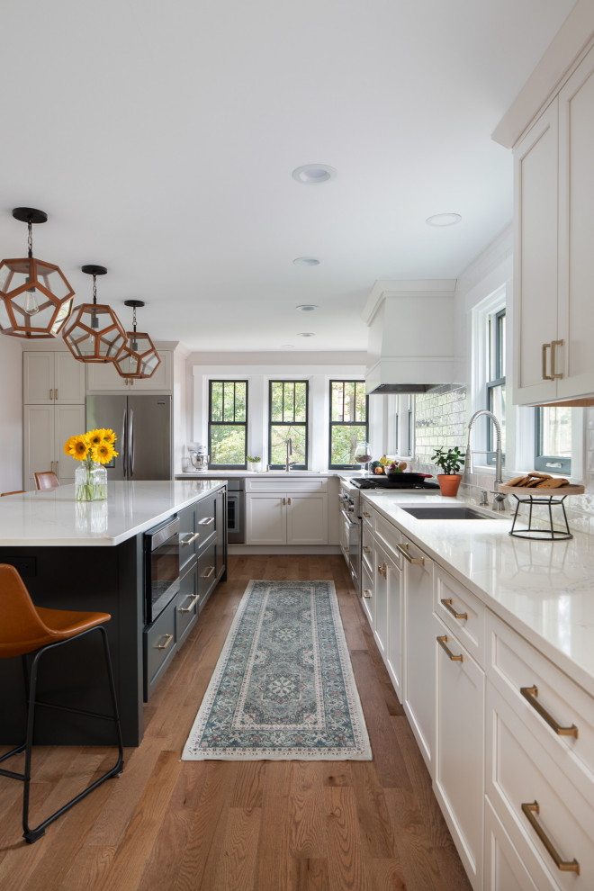 Eat-in kitchen - transitional l-shaped medium tone wood floor and brown floor eat-in kitchen idea in Other with a drop-in sink, shaker cabinets, green cabinets, quartzite countertops, white backsplash, subway tile backsplash, stainless steel appliances, an island and white countertops
